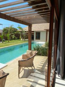 a patio with two chairs and a swimming pool at Vila Palmeiras in São Miguel do Gostoso