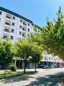 a white building with trees in front of it at Oasis Apartments in Bijeljina