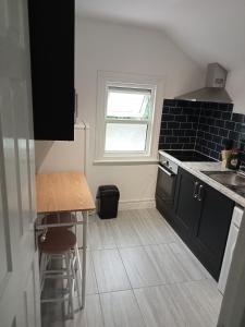 a kitchen with black cabinets and a table and a window at London Road Flats - Free WIFI, washing machine, smart TV, easy access to A50 in Derby