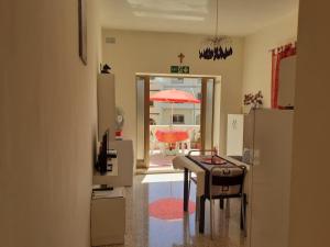 a kitchen with a table and an open door with an umbrella at Sunny large terrace studio apartment WiFi Airconditioners BBQ in Mellieħa