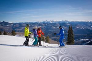 a group of four people standing on top of a ski slope at Greenbrier Townhouse 36 in Avon