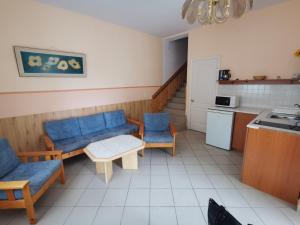 a room with blue chairs and a table and a kitchen at Anno 2000 in Balatonlelle