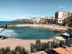 a swimming pool on a beach next to a beach at Arguineguin Beach Lux Solarium Suit in Arguineguín
