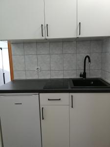 uma cozinha com um lavatório e armários brancos em Apartments Mato em Orebić
