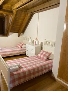 2 camas en un dormitorio con techos de madera en La Buhardilla de Sofía, en Sesué
