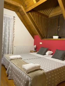 2 camas en una habitación con una pared roja en La Buhardilla de Sofía, en Sesué