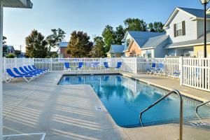 une piscine avec des chaises bleues et une clôture blanche dans l'établissement Walk to Ocean Myrtle Beach Home with Pool Access, à Myrtle Beach