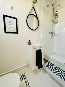 a white bathroom with a sink and a mirror at Apartment Direct Views of Eiffel Tower & Sacré-Coeur from Mezzanine - 10 mins to Paris Center in Paris