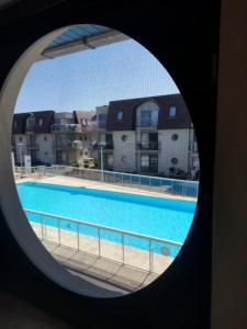 uma vista para uma piscina através de uma janela circular em appartement zee zon en zwem em Bredene-aan-Zee