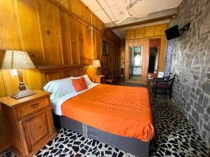 a bedroom with a bed with an orange comforter at Hotel Vitorina in Atlixco