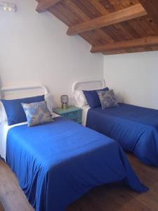 two beds in a room with blue sheets at Albergue de peregrinos Santa Marina in Molinaseca