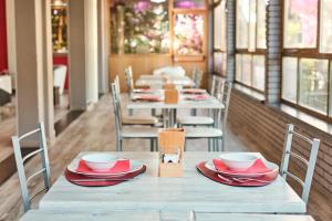 a row of tables in a restaurant with red dishes on them at Hotel Astoria in Bordighera
