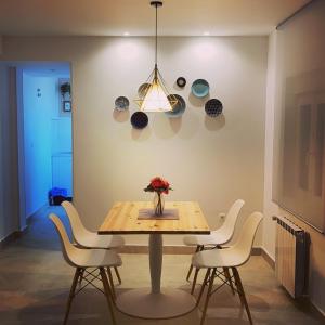 a dining room table with white chairs and a light fixture at Apartamentos La Estación M&S in Albacete