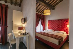 una camera con testiera rossa, tavolo e letto di Hotel Nazionale a Ferrara