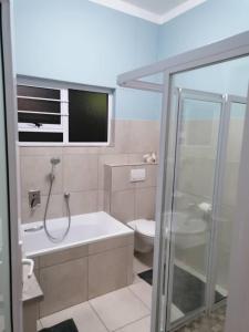 a bathroom with a shower and a sink and a toilet at Pebble Gardens Swakopmund in Swakopmund