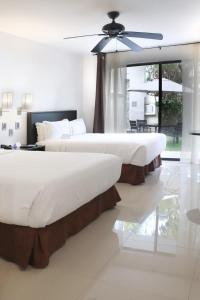 two beds in a bedroom with a ceiling fan at Casa Francisco in Cuernavaca
