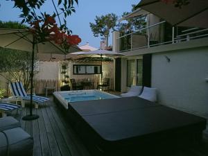un patio con piscina y sombrilla en Pomme de Pin et Mimosa en Grand-Village-Plage