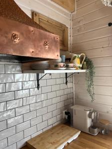 a kitchen with wooden walls and a shelf in a kitchen at Domek Anuszka in Sztutowo