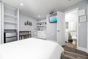 a white bedroom with a white bed and a tv at Shell on the Beach 103 - RENOVATED in Hollywood