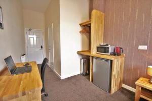 a room with a table and a microwave on a counter at Central Hotel Gloucester by RoomsBooked in Gloucester