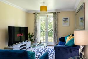a living room with a blue couch and a tv at 3 Bedroom Apartment, Free Parking & Fast WiFi, 65 Inch Smart TV in Milton Keynes