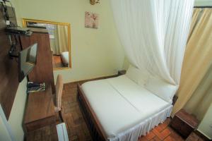 a small room with a bed with a white curtain at Al-Nisaa Hotel and Spa in Jinja
