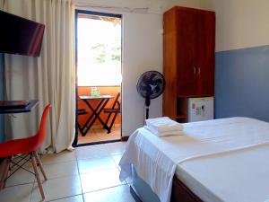 a room with a bed and a table and a window at FAROL BEACH Suítes in Salvador