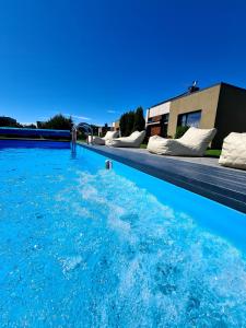 uma piscina com água azul em frente a uma casa em SEA GARDEN atostogų namai su šildomu baseinu, Kunigiškiai em Palanga