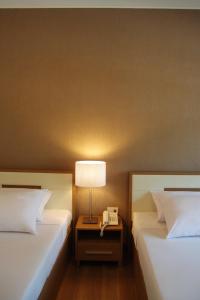 2 camas en una habitación con lámpara y teléfono en Korat Resort Hotel, en Nakhon Ratchasima