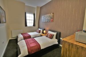 a hotel room with two beds and a television at Central Hotel Gloucester by RoomsBooked in Gloucester