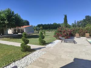 a park with a bench and some bushes and flowers at La Plénitude in Le Thor