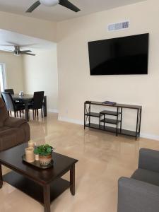 ein Wohnzimmer mit einem TV und einem Tisch in der Unterkunft Newly Remodeled Family Friendly 3B/2B House in Henderson