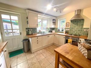 a large kitchen with white cabinets and a sink at Willow Cottage on the upper River Bure in Aylsham