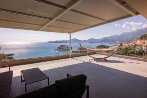 a room with a view of the ocean and a hammock at Vertmont Villa in Sveti Stefan