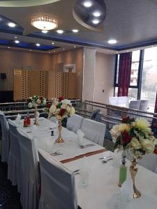 a conference room with white tables and flowers in vases at Hostel le Coin d'Or in Fort de lʼEau