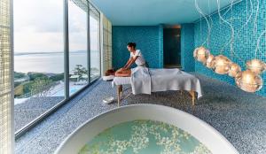 a woman sitting in a bathroom with a tub at COMO Point Yamu, Phuket- SHA Extra Plus in Ban Pa Khlok