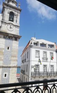 un edificio con una torre de reloj junto a un edificio en Legendary Bay Suite Temática, en Seixal