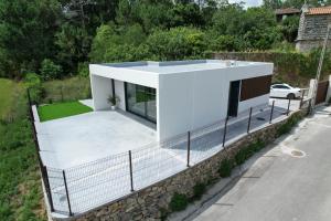 a white house on a stone wall with a driveway at Casiña de Cris in Boiro