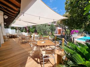 una terraza de madera con mesas, sillas y sombrilla en Eco Hotel Montemerlo, en Fetovaia