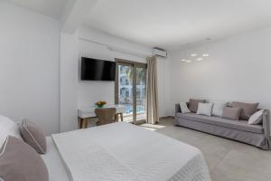 a white living room with a couch and a tv at Stavros Beach Hotel in Stavros