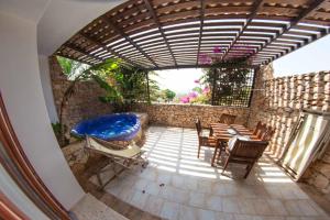 eine Terrasse mit einem Whirlpool, einem Tisch und Stühlen in der Unterkunft Cupola Bianca Resort in Lampedusa