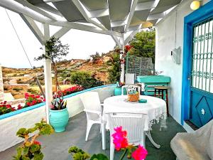 - une table et des chaises blanches sur une terrasse fleurie dans l'établissement Rou Garden House, à Karpathos