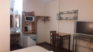 een woonkamer met een televisie en een tafel met stoelen bij Teilen in Villa General Belgrano