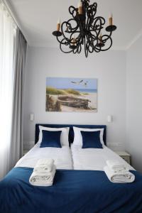 ein Schlafzimmer mit einem blauen und weißen Bett mit einem Kronleuchter in der Unterkunft Sea Sopot Apartments by OneApartments in Sopot