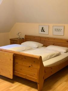 a large wooden bed with white sheets and pillows at das Eppelsheimer in Undenheim +14 photos