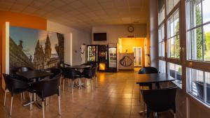un restaurante con mesas y sillas en una habitación con ventanas en Albergue Espiritu Xacobeo en O Pedrouzo
