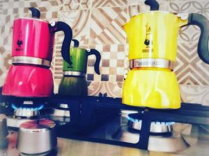 four different colored coffee pots sitting on a shelf at B&B Libertà Marsala in Marsala
