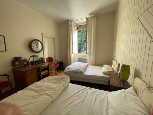 a bedroom with two beds and a clock on the wall at La Maison in Saint-Béat