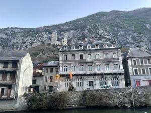 a group of buildings next to a river with a mountain at La Maison in Saint-Béat