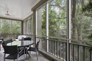 un porche cubierto con mesa, sillas y ventanas en 8121 Wendover Dunes en Hilton Head Island